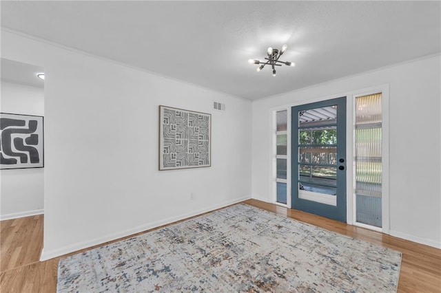 entryway with a chandelier, wood finished floors, and baseboards