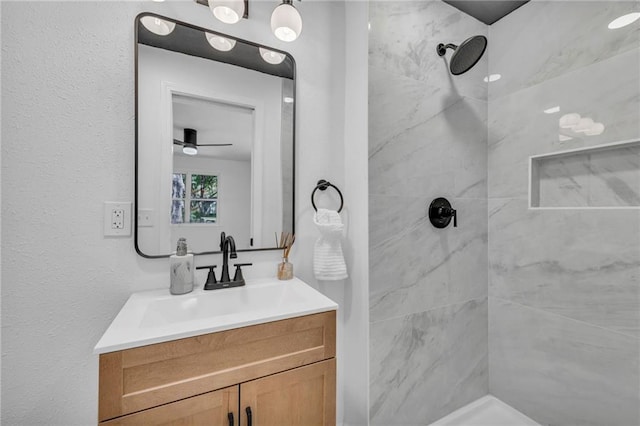 full bath with a tile shower, vanity, and a ceiling fan