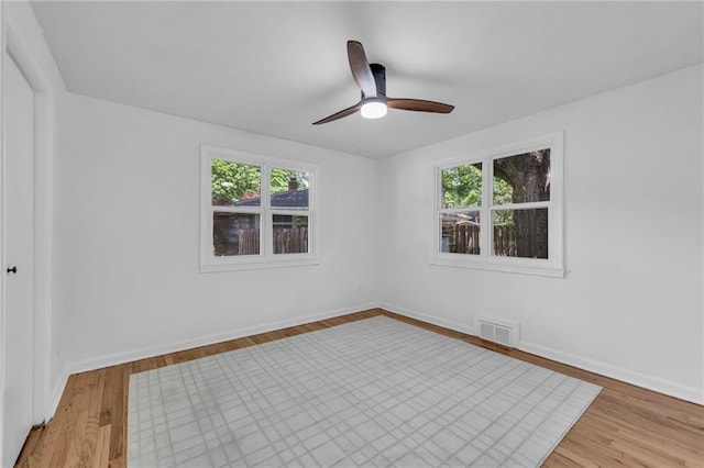 spare room featuring plenty of natural light, wood finished floors, a ceiling fan, and baseboards