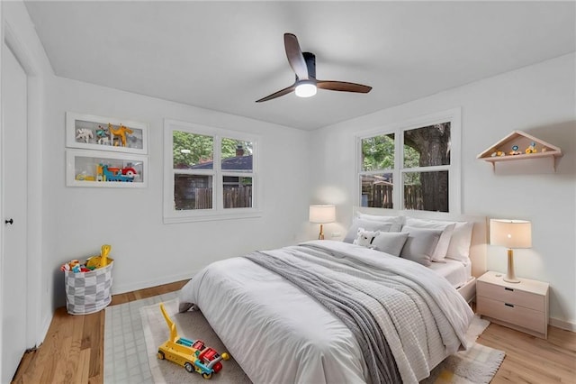 bedroom featuring light wood-style floors, baseboards, and a ceiling fan