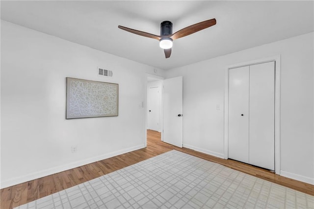 unfurnished bedroom with baseboards, wood finished floors, ceiling fan, and a closet