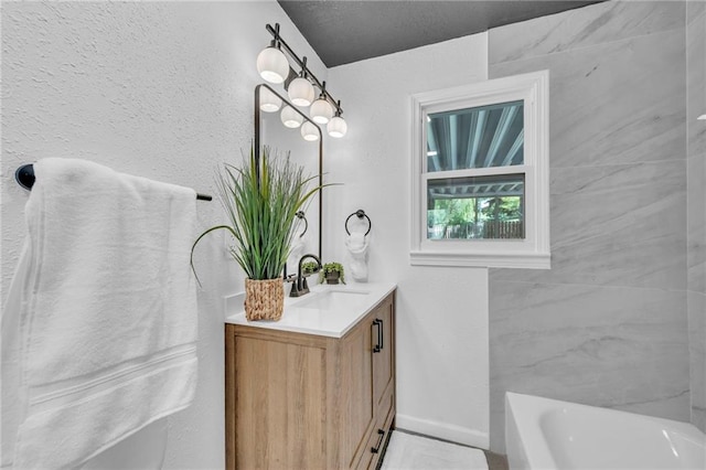 full bath featuring a tub, vanity, and baseboards