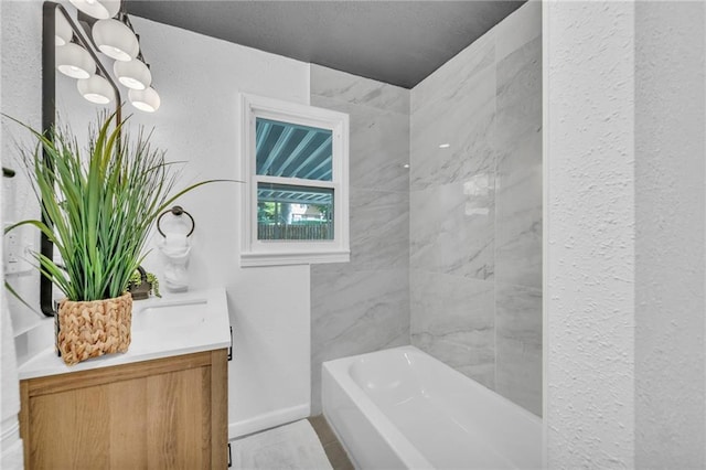 full bath with a tub, vanity, and a textured wall