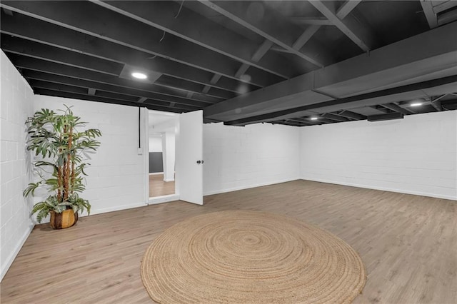 finished below grade area featuring wood finished floors and concrete block wall