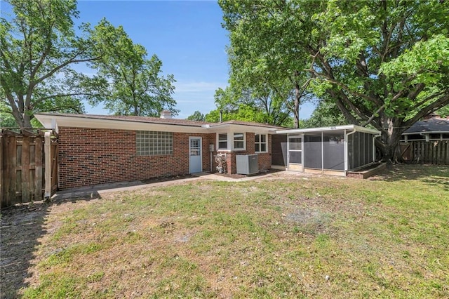 rear view of property featuring a sunroom, brick siding, and cooling unit