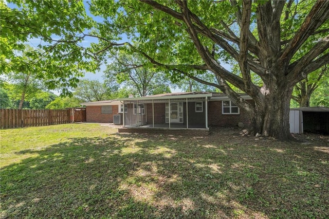 rear view of property with a sunroom, brick siding, and central AC