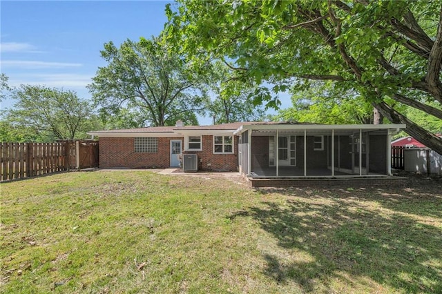 back of house with a sunroom, cooling unit, brick siding, and a chimney