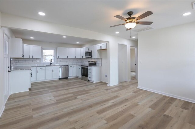 15608 E 267th St, Harrisonville, MO 64701 - kitchen featuring stainless steel appliances, decorative backsplash, light wood-style flooring, a ceiling fan, and white cabinets
