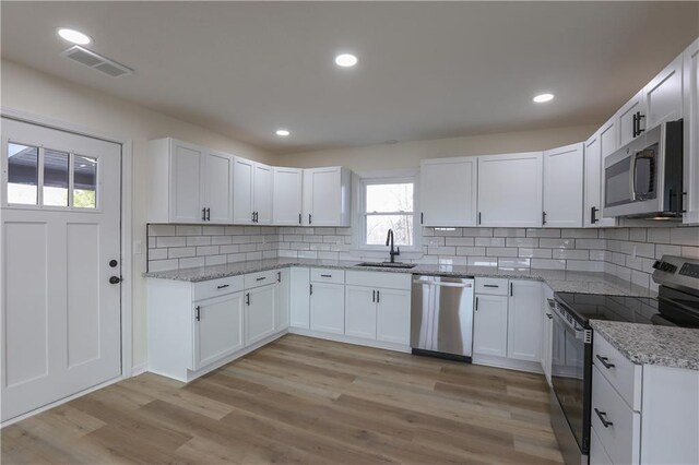 15608 E 267th St, Harrisonville, MO 64701 - kitchen featuring stainless steel appliances, a sink, light stone countertops, decorative backsplash, and white cabinets