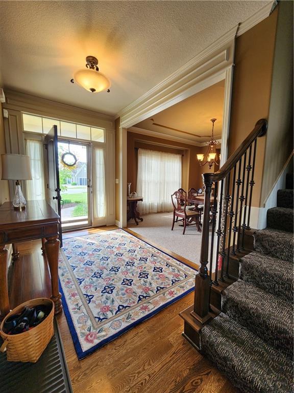 14650 NW 66th Ter, Parkville, MO 64152 - foyer entrance with a chandelier, ornamental molding, stairway, wood finished floors, and a textured ceiling