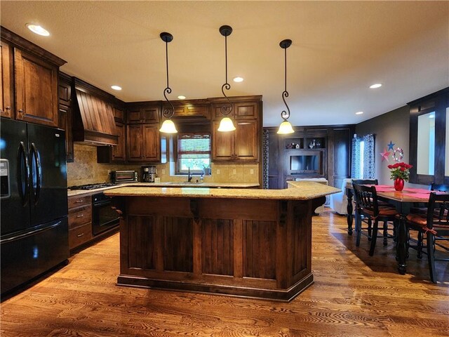 14650 NW 66th Ter, Parkville, MO 64152 - kitchen with black appliances, premium range hood, wood finished floors, a center island, and backsplash