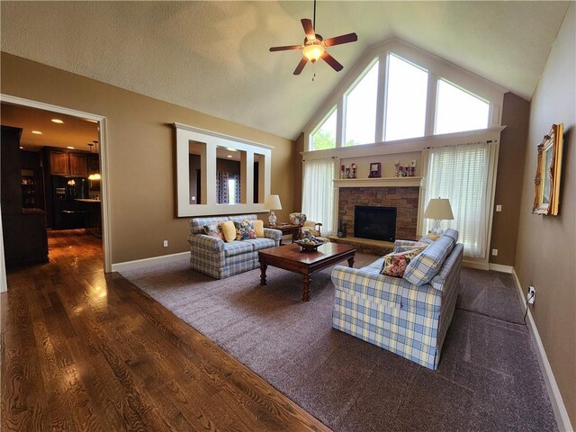 14650 NW 66th Ter, Parkville, MO 64152 - living room featuring a ceiling fan, baseboards, dark wood-type flooring, a stone fireplace, and high vaulted ceiling