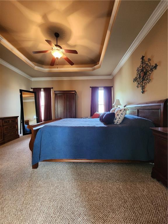 14650 NW 66th Ter, Parkville, MO 64152 - carpeted bedroom featuring a tray ceiling, crown molding, and a ceiling fan
