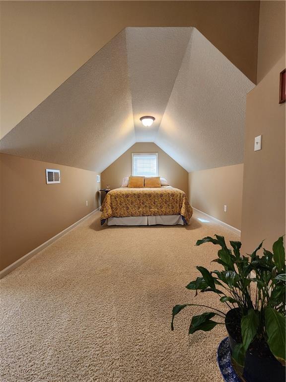 14650 NW 66th Ter, Parkville, MO 64152 - bedroom featuring carpet floors, vaulted ceiling, baseboards, and a textured ceiling