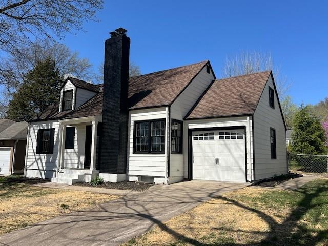 view of front of property with an attached garage, a chimney, fence, concrete driveway, and roof with shingles