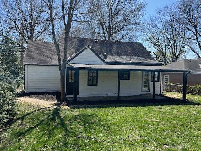 rear view of property with a lawn, a porch, and roof with shingles