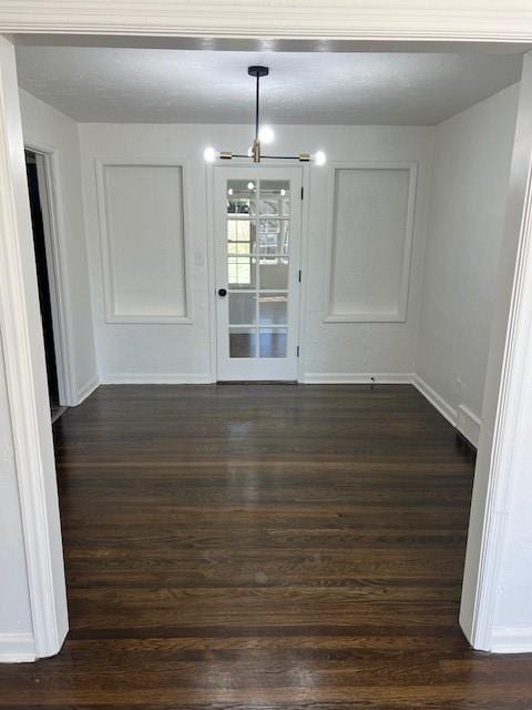 unfurnished dining area with baseboards and dark wood-type flooring