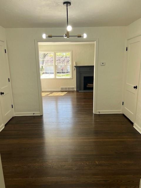 unfurnished dining area featuring dark wood finished floors, baseboards, and a fireplace