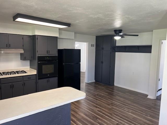 kitchen with black appliances, ceiling fan, dark wood-style floors, baseboards, and under cabinet range hood