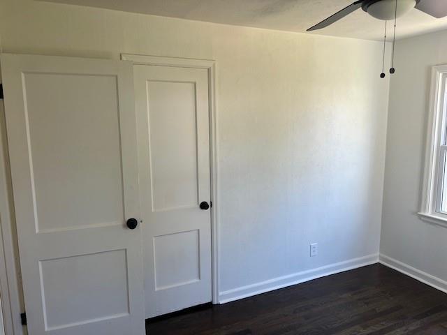 unfurnished bedroom featuring baseboards, dark wood finished floors, and ceiling fan