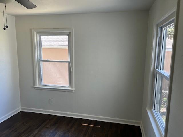 spare room with dark wood-type flooring and baseboards