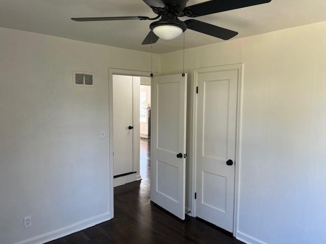unfurnished bedroom with baseboards, dark wood-style flooring, and ceiling fan