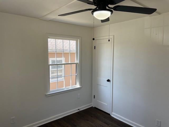 empty room featuring a ceiling fan, dark wood-type flooring, and baseboards