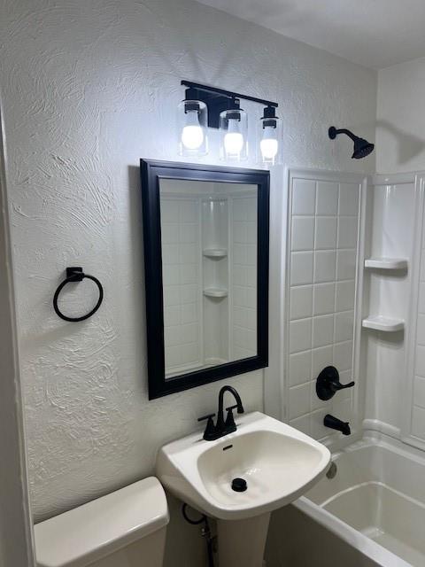 full bath featuring a textured wall, toilet, shower / bathtub combination, and a sink