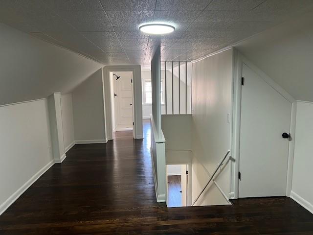 bonus room with dark wood-style flooring, baseboards, and vaulted ceiling