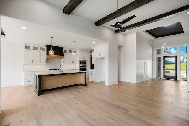 kitchen featuring stainless steel appliances, a ceiling fan, light wood-type flooring, white cabinets, and beam ceiling