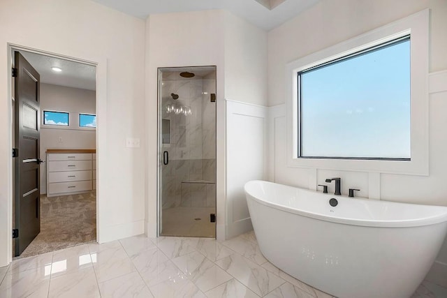 bathroom featuring marble look tiles, a shower stall, and a freestanding tub