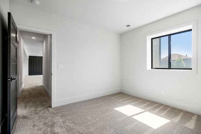 carpeted spare room featuring a smoke detector and baseboards