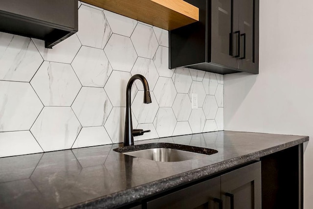kitchen with a sink, decorative backsplash, and dark stone counters