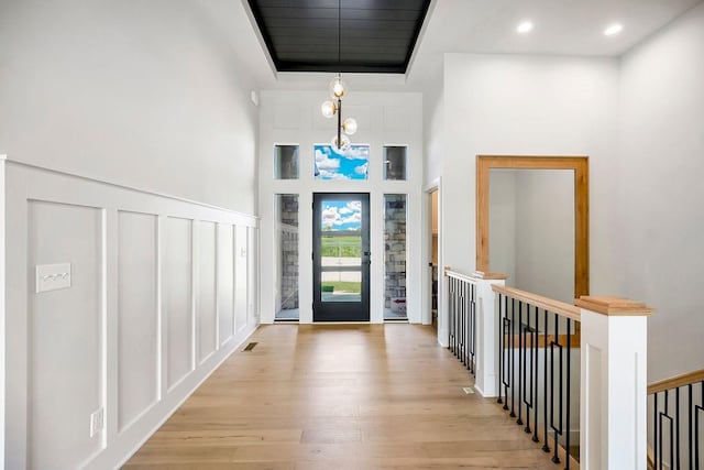 entrance foyer featuring light wood finished floors, a decorative wall, and a high ceiling