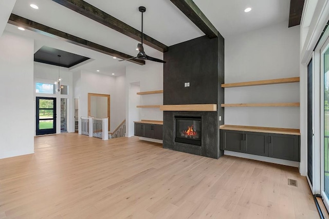 unfurnished living room with light wood-style floors, beamed ceiling, a large fireplace, ceiling fan, and recessed lighting