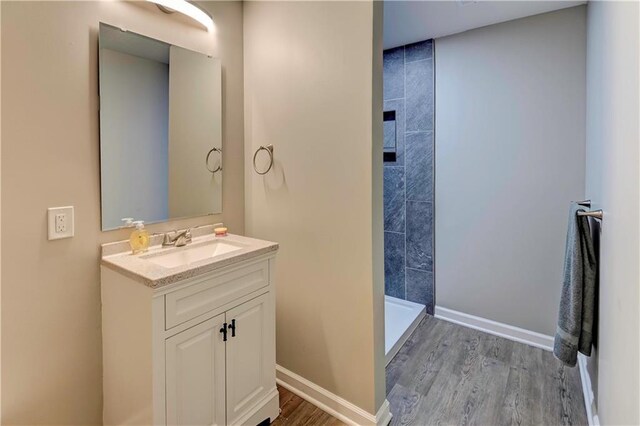 16253 W Briarwood Ct, Olathe, KS 66062 - bathroom with vanity, wood finished floors, tiled shower, and baseboards