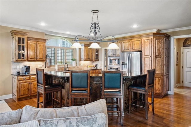 10233 N Prospect Ave, Kansas City, MO 64155 - kitchen featuring stainless steel appliances, a center island, brown cabinetry, a kitchen bar, and crown molding