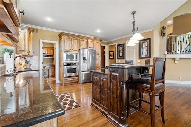 10233 N Prospect Ave, Kansas City, MO 64155 - kitchen with appliances with stainless steel finishes, a sink, wood finished floors, ornamental molding, and a kitchen bar