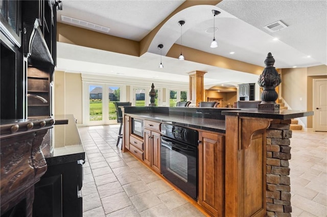 10233 N Prospect Ave, Kansas City, MO 64155 - kitchen with black oven, brown cabinetry, a kitchen breakfast bar, a textured ceiling, and open floor plan