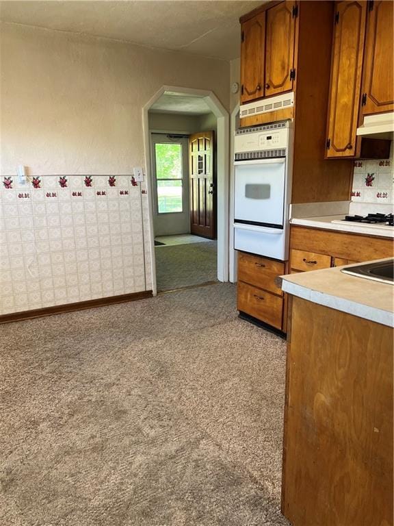 5720 NW 51st St, Kansas City, MO 64151 - kitchen with a warming drawer, white oven, arched walkways, brown cabinets, and light countertops