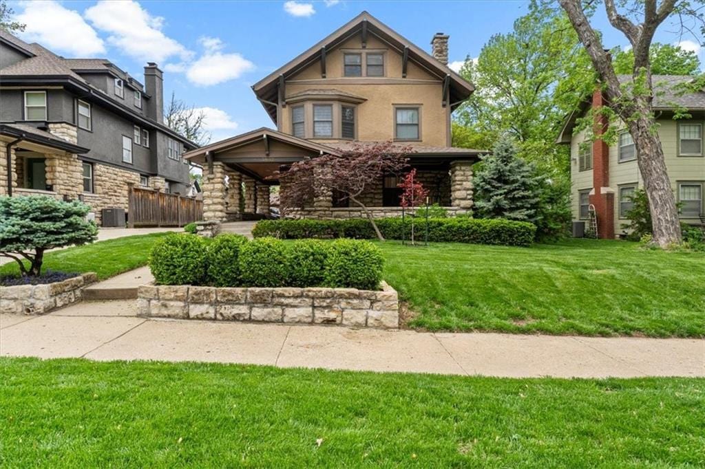 3632 Pennsylvania Ave, Kansas City, MO 64111 - view of front of house with a chimney, a front yard, central air condition unit, and stone siding