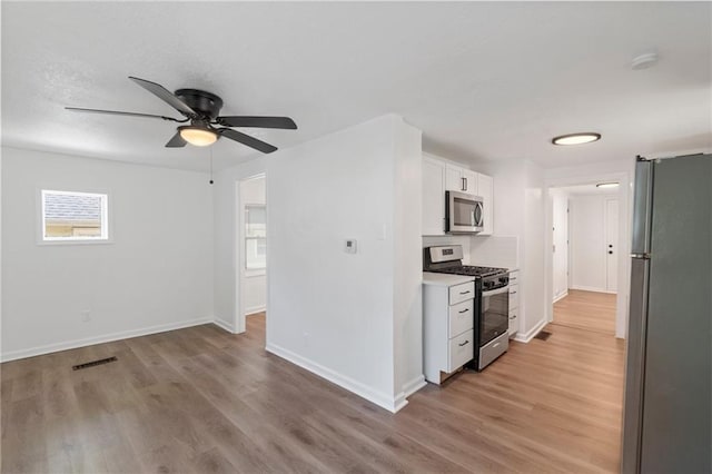228 N 26th St, Kansas City, KS 66102 - kitchen featuring appliances with stainless steel finishes, light wood-type flooring, white cabinets, and baseboards