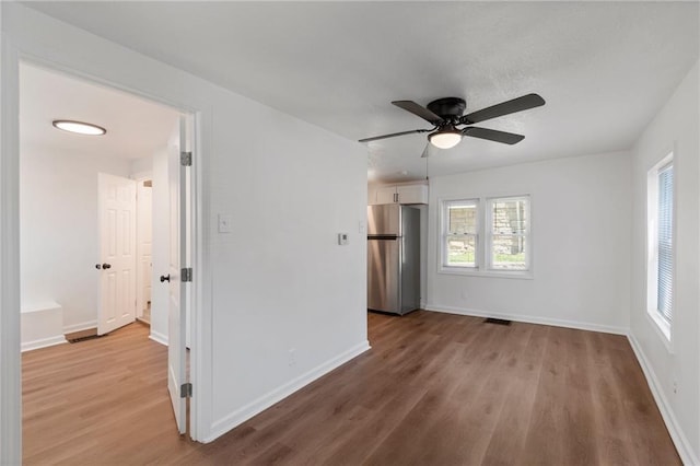 228 N 26th St, Kansas City, KS 66102 - unfurnished bedroom with freestanding refrigerator, multiple windows, and wood finished floors