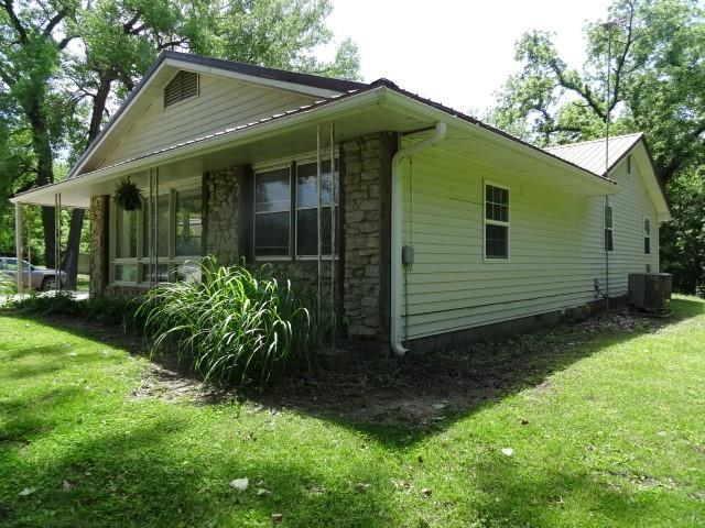 6780 SW County Road 2007th Rd, Rich Hill, MO 64779 - view of home's exterior featuring stone siding, a lawn, and central AC
