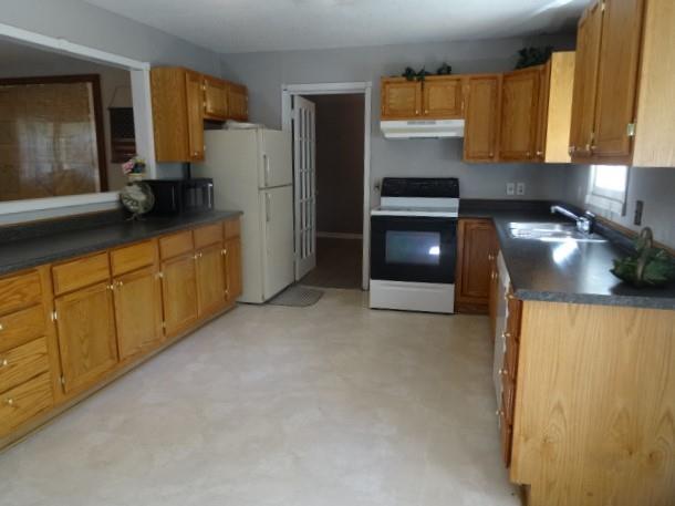 6780 SW County Road 2007th Rd, Rich Hill, MO 64779 - kitchen featuring electric range, under cabinet range hood, a sink, dark countertops, and brown cabinets