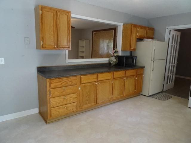 6780 SW County Road 2007th Rd, Rich Hill, MO 64779 - kitchen featuring freestanding refrigerator, dark countertops, brown cabinets, and black microwave