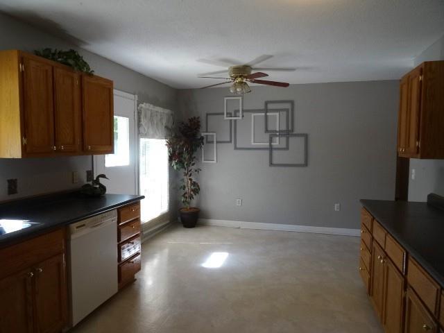6780 SW County Road 2007th Rd, Rich Hill, MO 64779 - kitchen with white dishwasher, dark countertops, baseboards, a ceiling fan, and brown cabinets