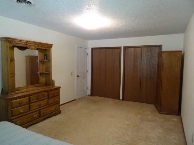 6780 SW County Road 2007th Rd, Rich Hill, MO 64779 - bedroom with light carpet, multiple closets, and a textured ceiling