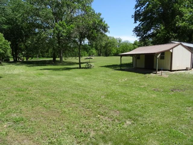 6780 SW County Road 2007th Rd, Rich Hill, MO 64779 - view of grassy yard featuring a pole building, an outbuilding, and view of wooded area