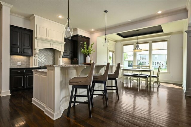 15601 Windsor St, Overland Park, KS 66224 - kitchen featuring ornamental molding, dark wood-style flooring, decorative backsplash, a breakfast bar, and light stone counters